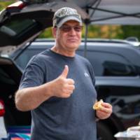 Patron holds up thumbs up sign during tailgate.